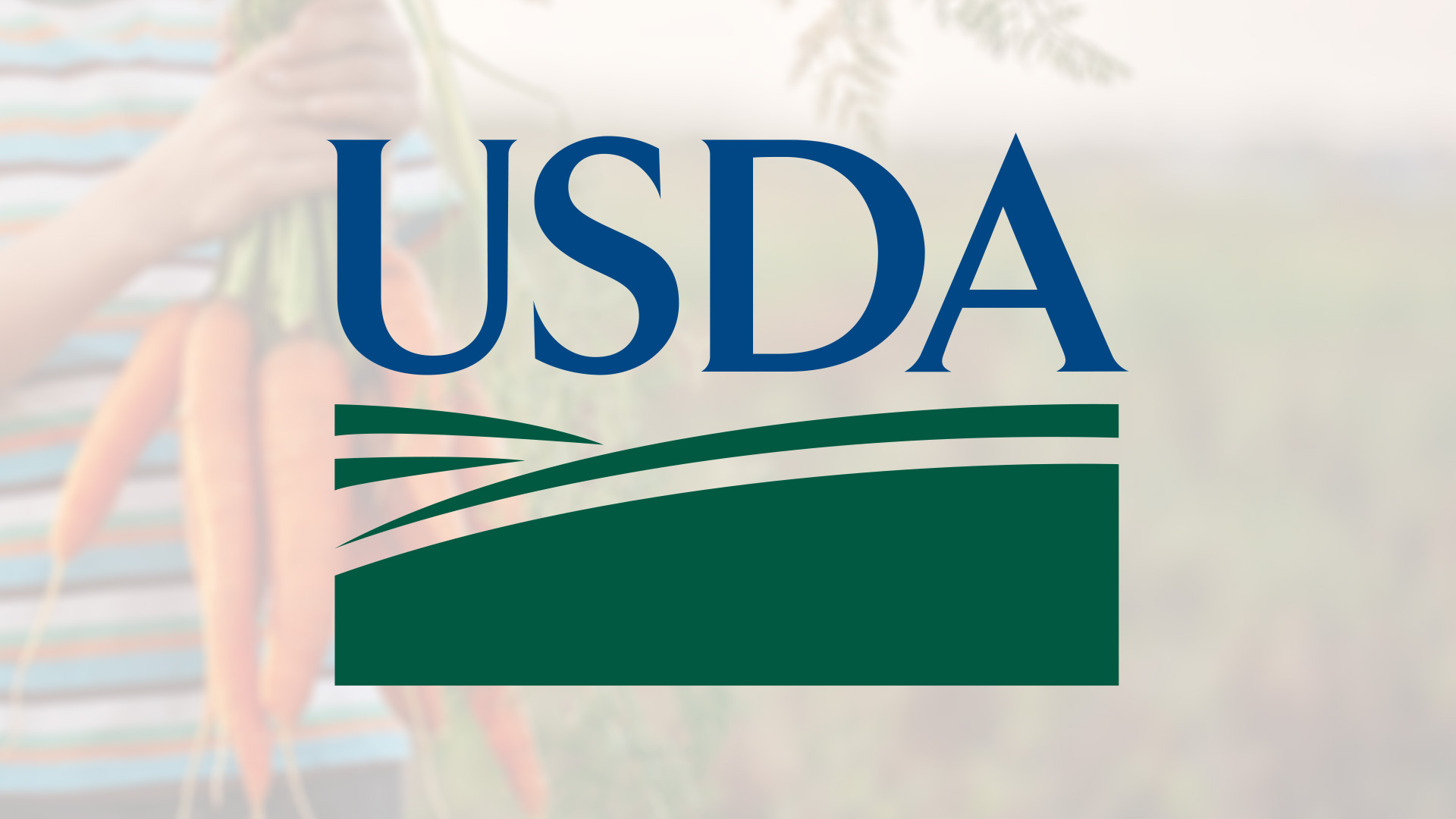 Image of the USDA logo with a blurred background of a person holding freshly harvested carrots.